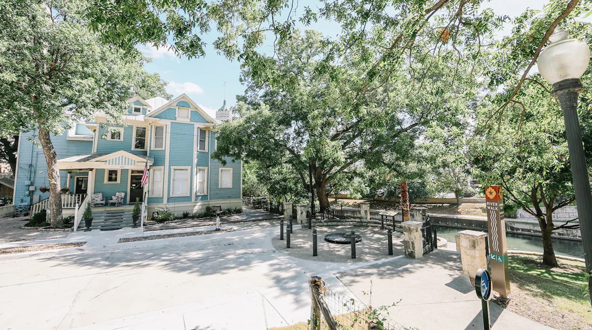 A light blue house surrounded by greenery and a small seating area.