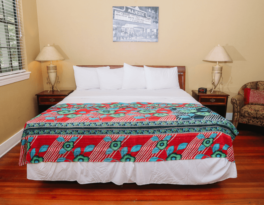 Cozy bedroom featuring a colorful patterned bedspread and large windows.